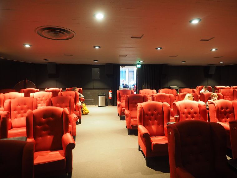 Rows of red velvet armchairs in a small cinema